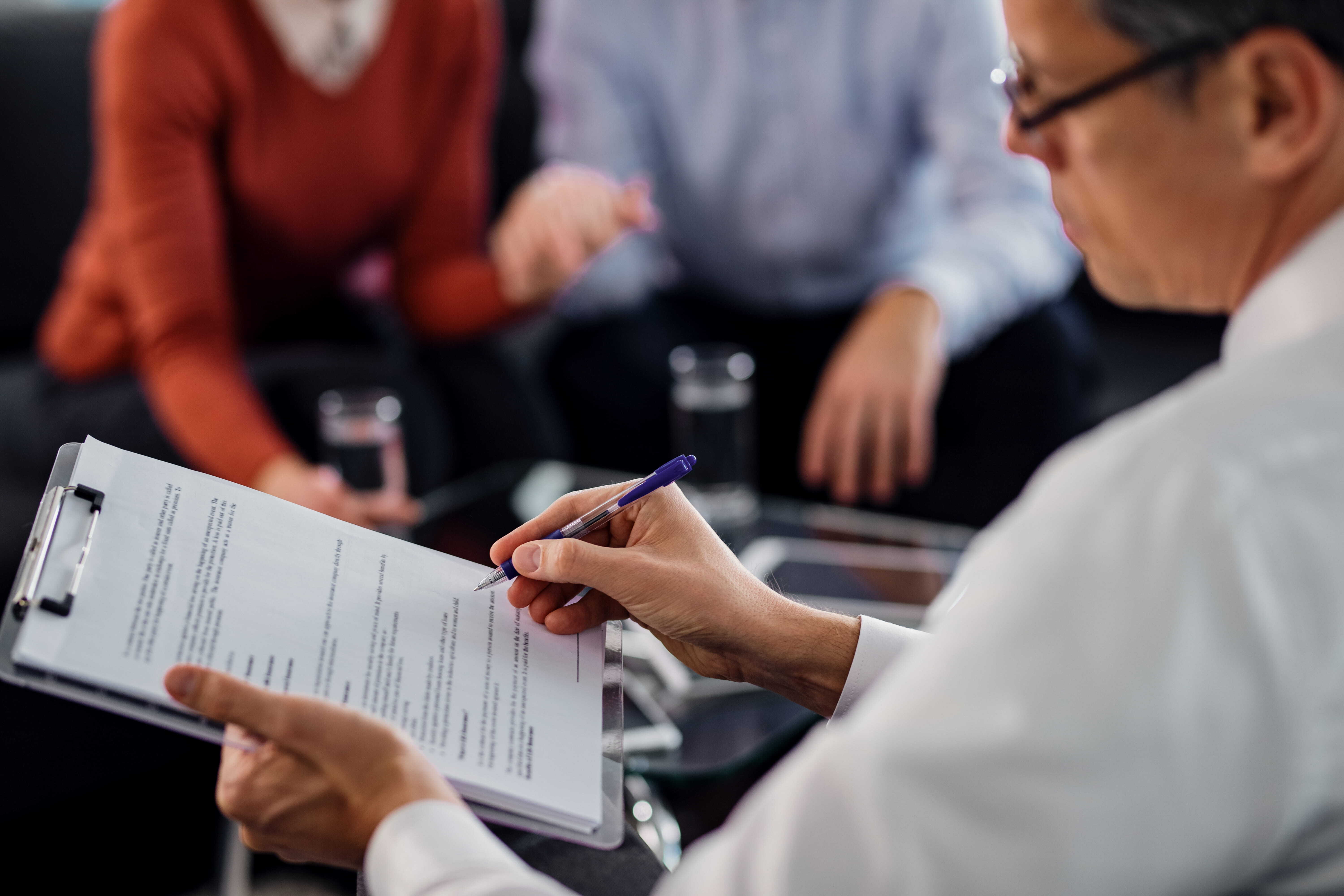 A doctor reviewing paperwork during a private health insurance consultation with patients.